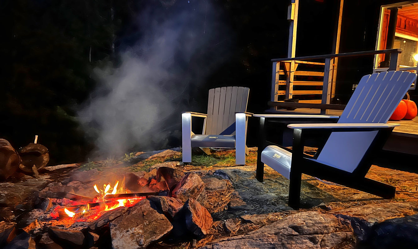 Two Modern Heated Muskoka chairs in Silver and Slate around a lit campfire
