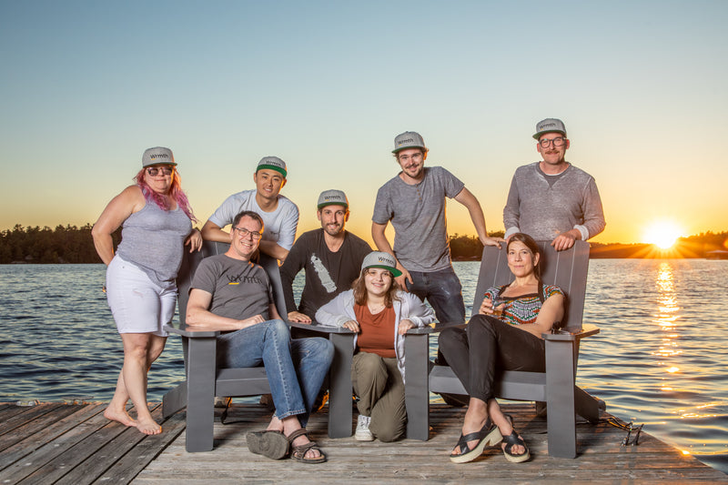 A posed staff photo on a jetty deck next to a sun setting
